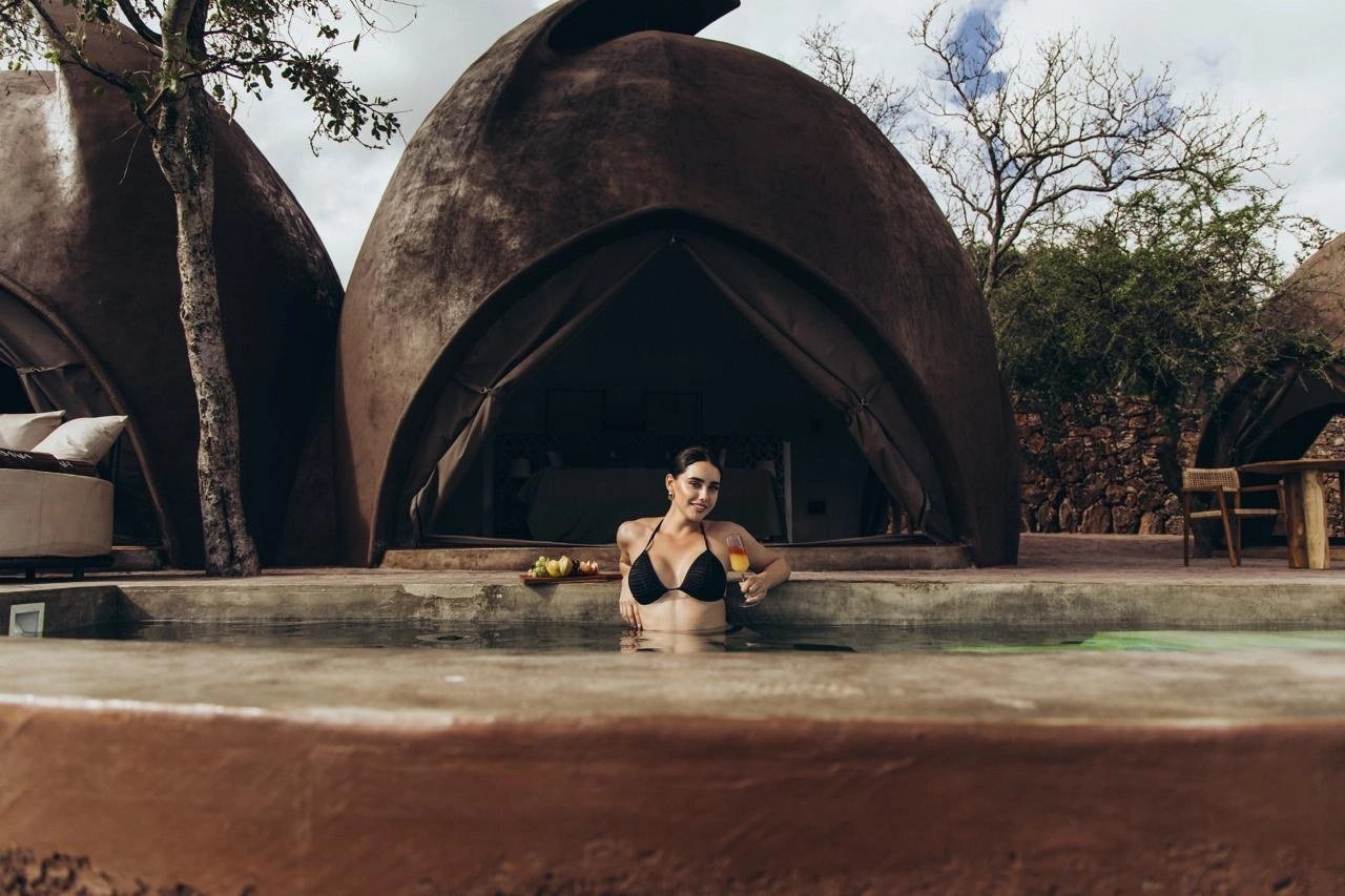 Lantern-lit plunge pool glows beside a dome suite at dusk at Asanja Ruaha