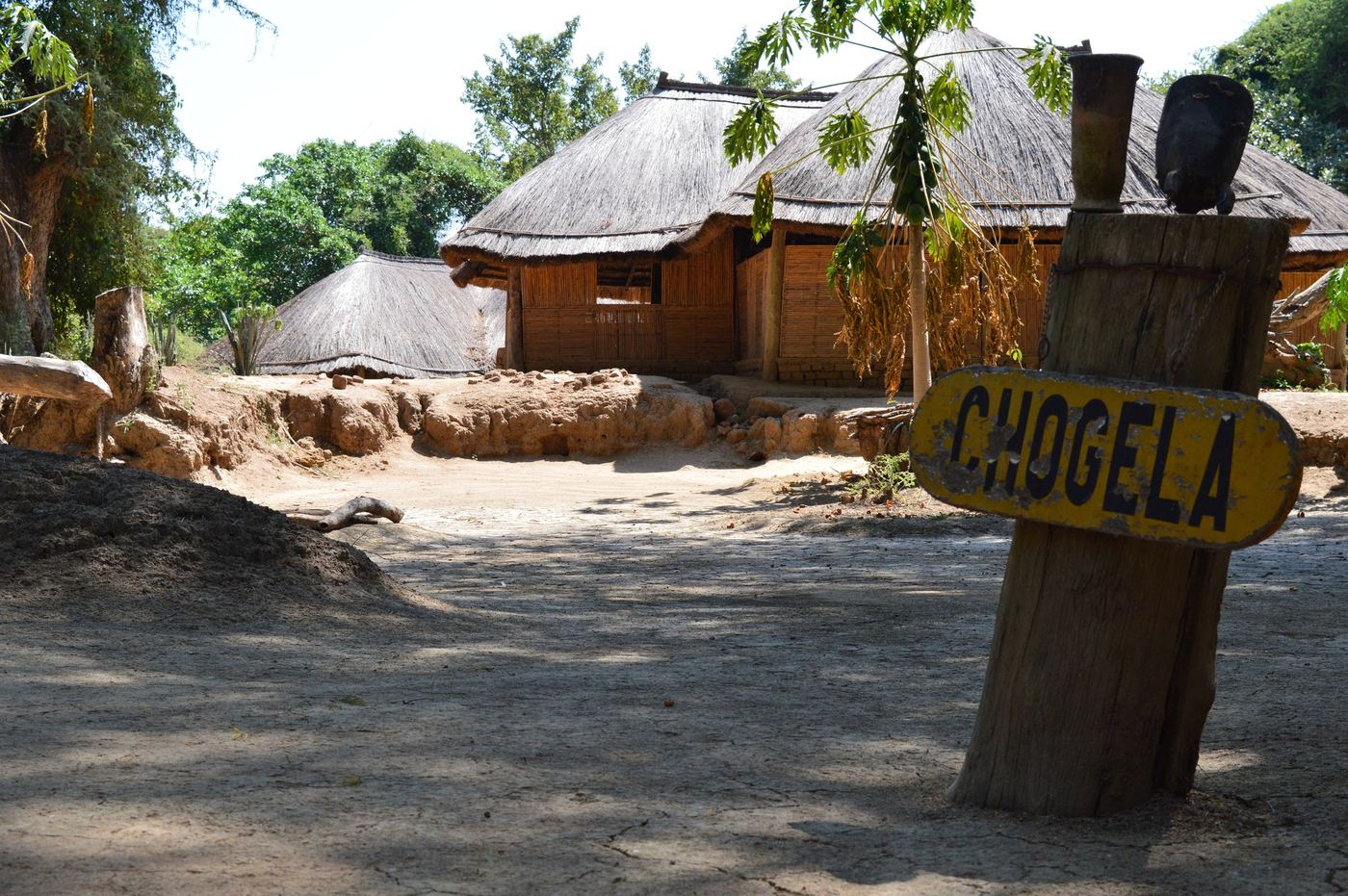 Thatched huts line a sandy path leading into Chogela Safari Camp