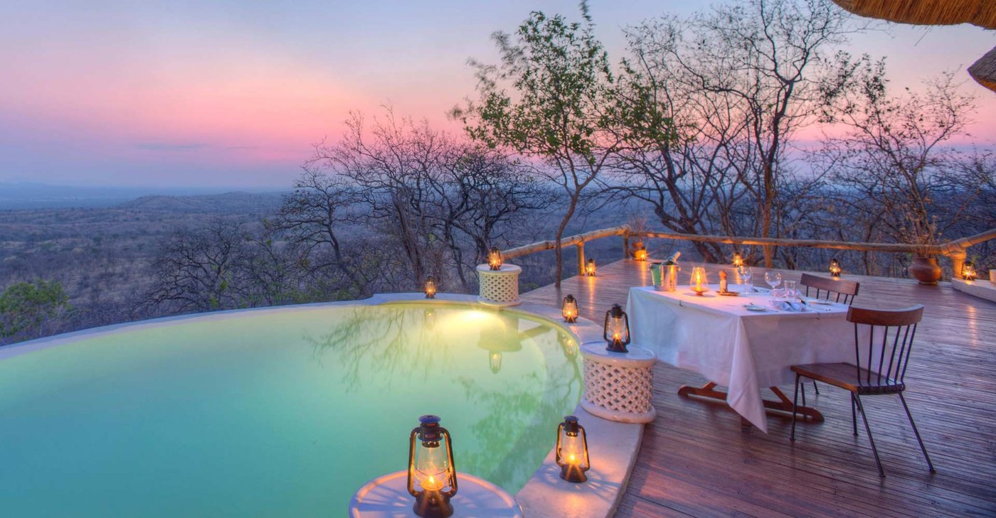 Infinity pool and candlelit dinner table above the valley at Ikuka Safari Camp in Ruaha