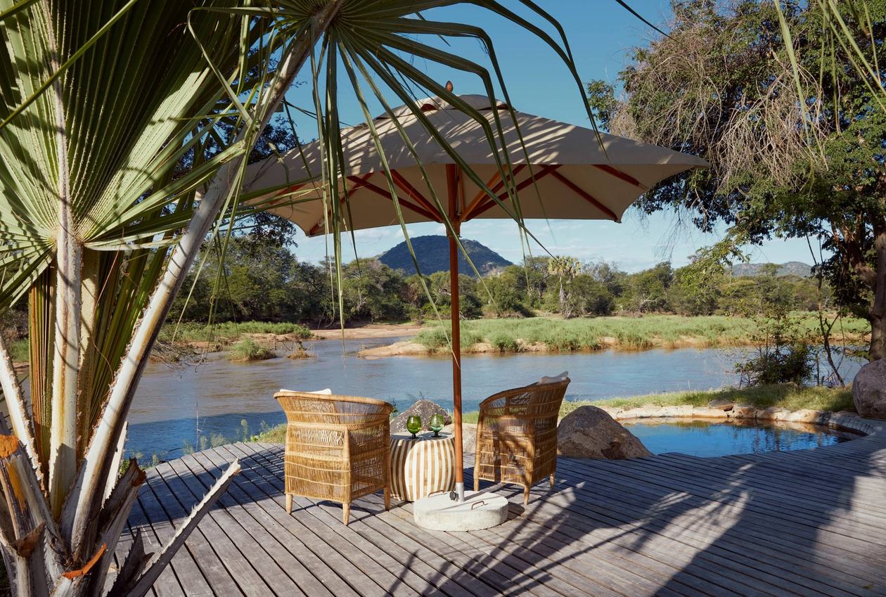 Shaded deck with lounge chairs overlooking the river at Jongomero Camp