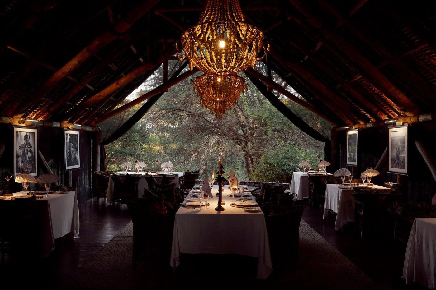 Candlelit dining room glows beneath a woven chandelier at Jongomero Camp