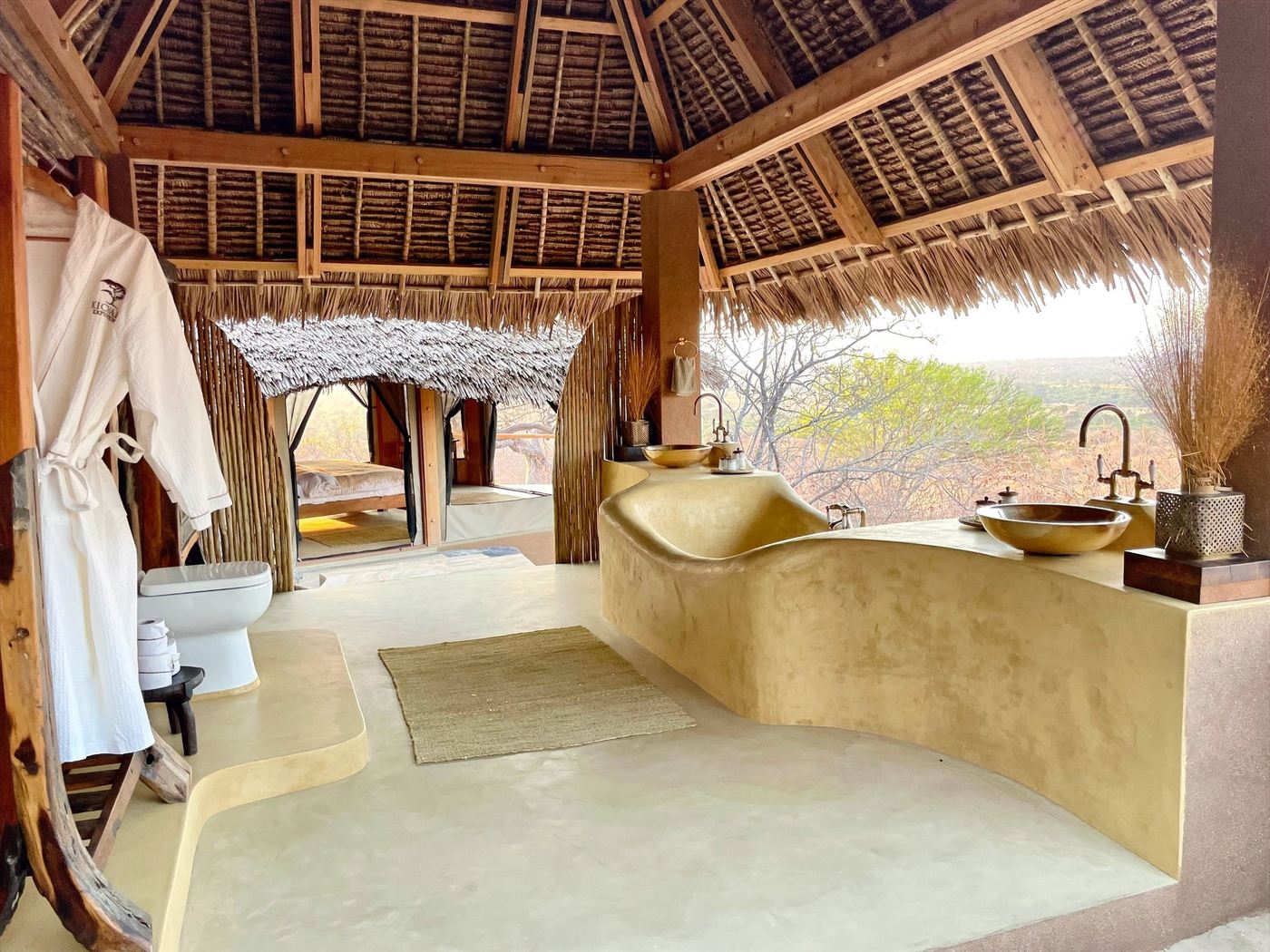 Curved clay vanity with twin basins in an open-air bathroom at Kichaka Expeditions