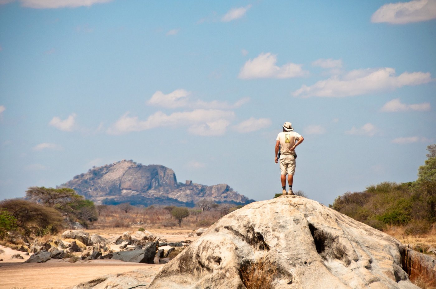 Guide stands atop a boulder surveying distant hills near Kichaka Expeditions