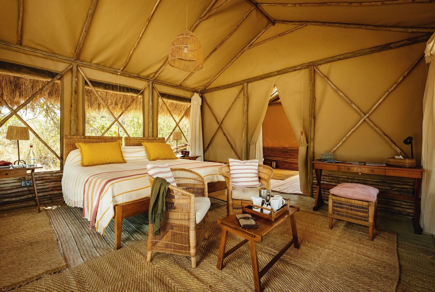 Canvas-walled tented bedroom with yellow cushions and warm lamplight at Kigelia Ruaha