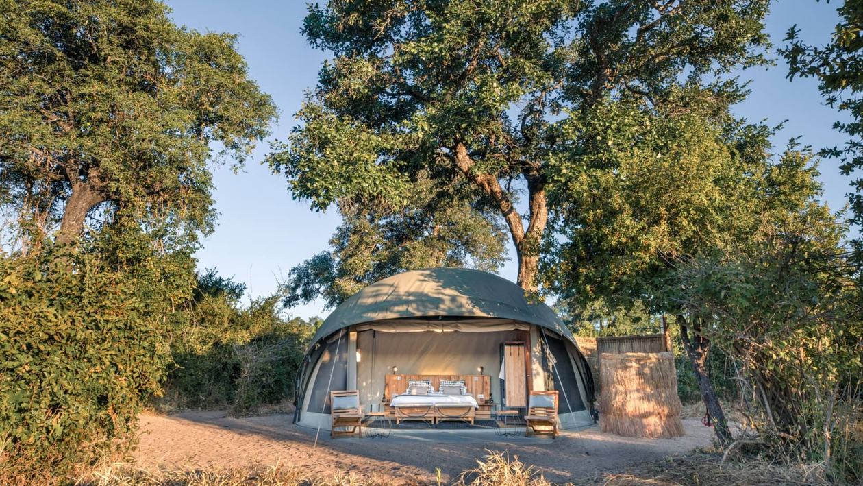 Domed safari tent nestled among trees on the Mwagusi riverbank at Kokoko Camp in Ruaha