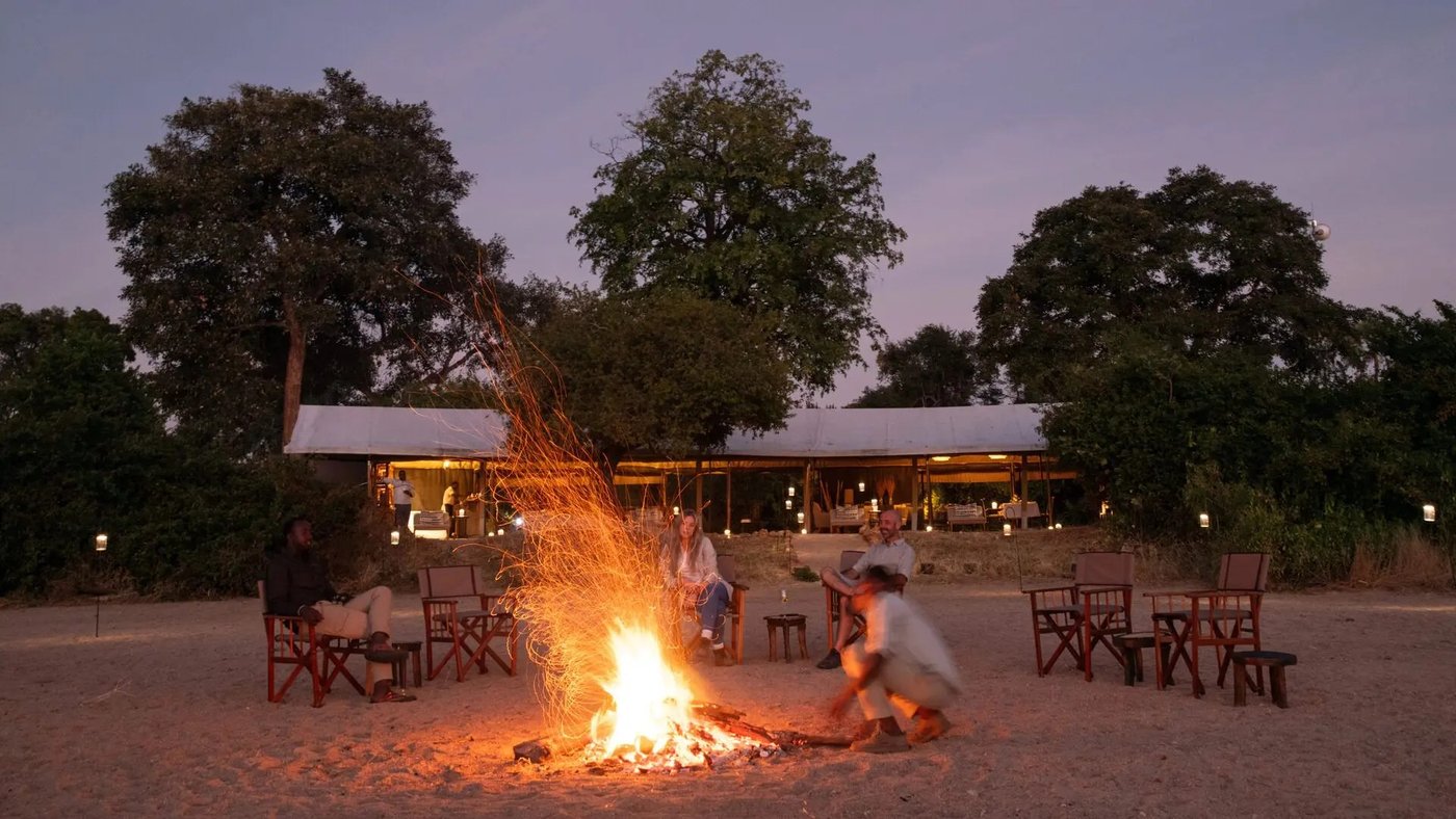 Guests gather around an open campfire for dinner under the stars at Kokoko Camp