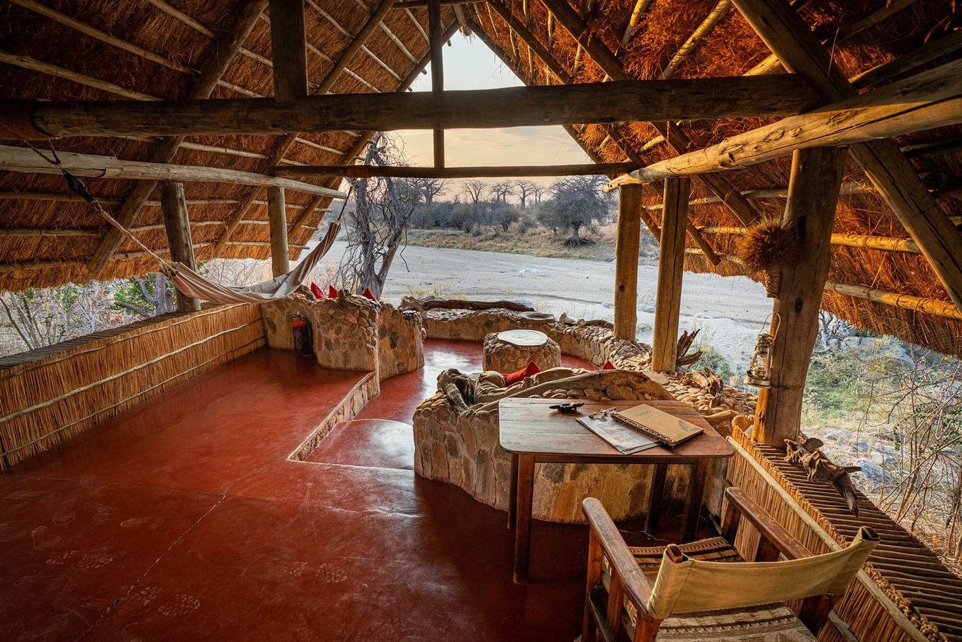 Round thatched lounge with red floors opens to river views at Mwagusi Safari Camp