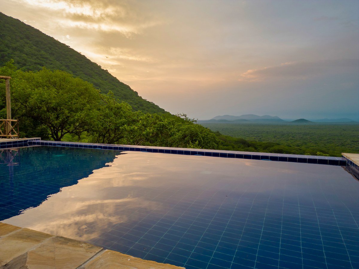 Infinity pool glows under a dramatic sunset sky at Ruaha Hilltop Lodge