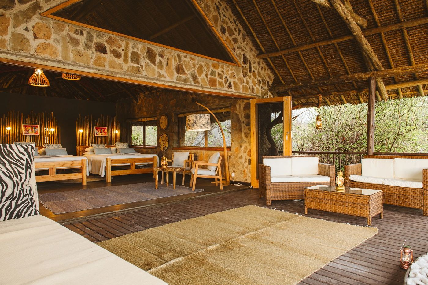 Stone-and-thatch suite with twin beds and an open-air lounge area at Ruaha River Lodge