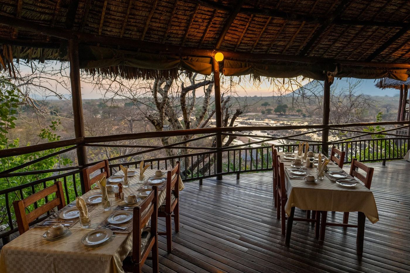 Dining table set on a riverside deck above the rapids at Ruaha River Lodge