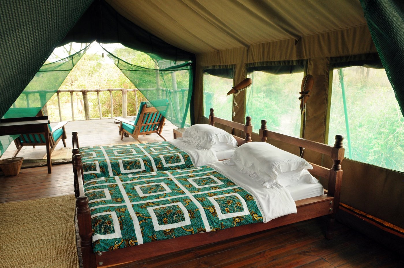 Twin tented beds with teal and white patterned linens at Tandala Tented Camp