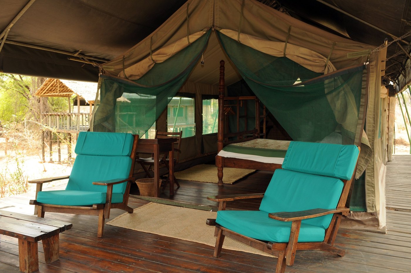 Teal lounge chairs on a shaded deck looking into the bush at Tandala Tented Camp
