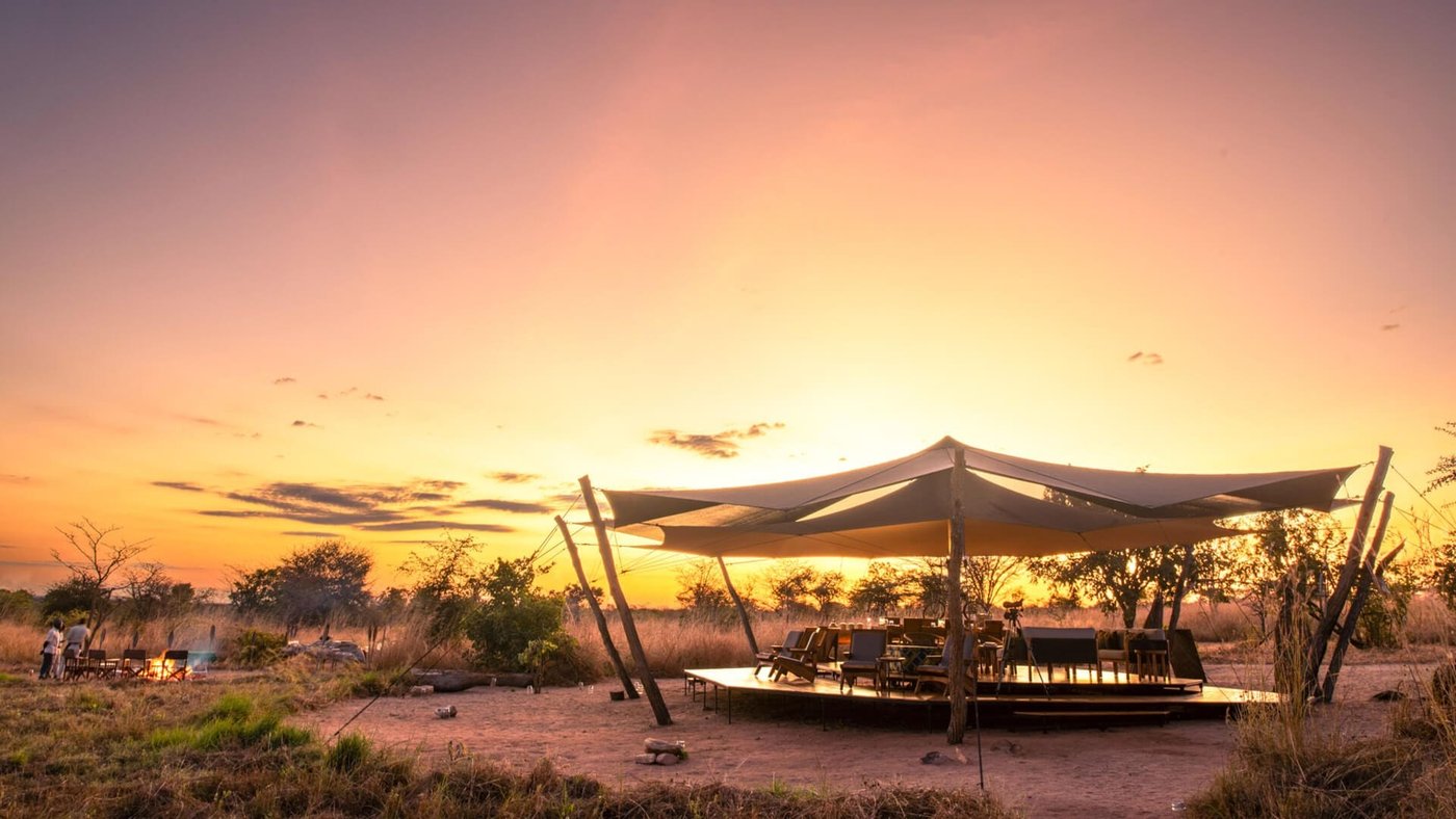 Open-sided tent camp with a sweeping canvas roof at sunset at Usangu Expedition Camp in Ruaha