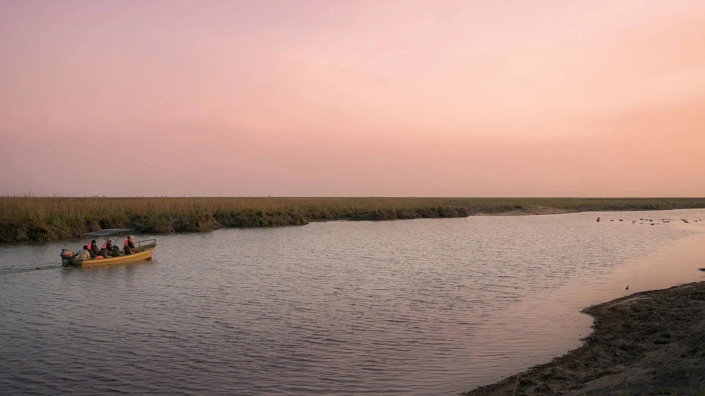 Small boat drifting on the river at dusk near Usangu Expedition Camp