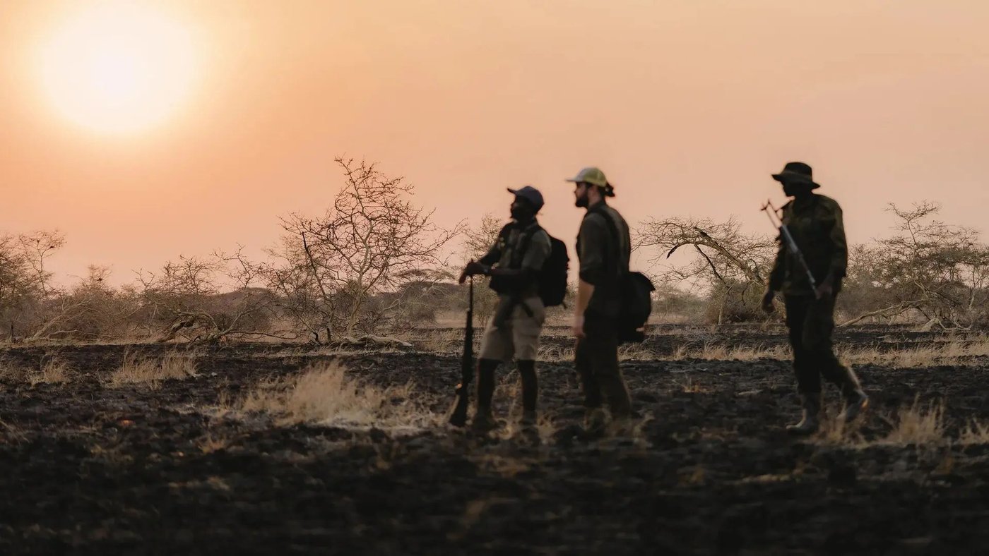 Research team crosses a burned landscape in golden light near Usangu Expedition Camp